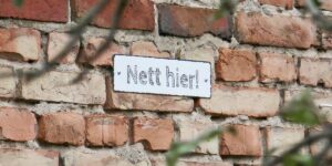 OJC-Greifswald: Termine. Nett hier! Ein Schild an einer Ziegelsteinmauer.